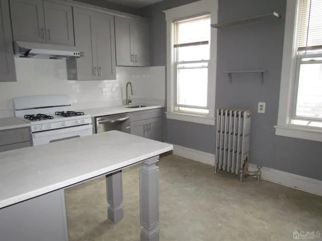 a kitchen with a stove a sink and a window