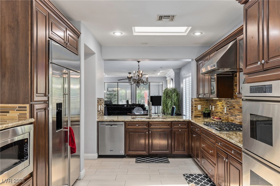 3 Chatmoss Road Henderson, NV 89052 - Photo 10 of 41 Kitchen featuring built in appliances, a sink, tasteful backsplash, a chandelier, and light stone counters