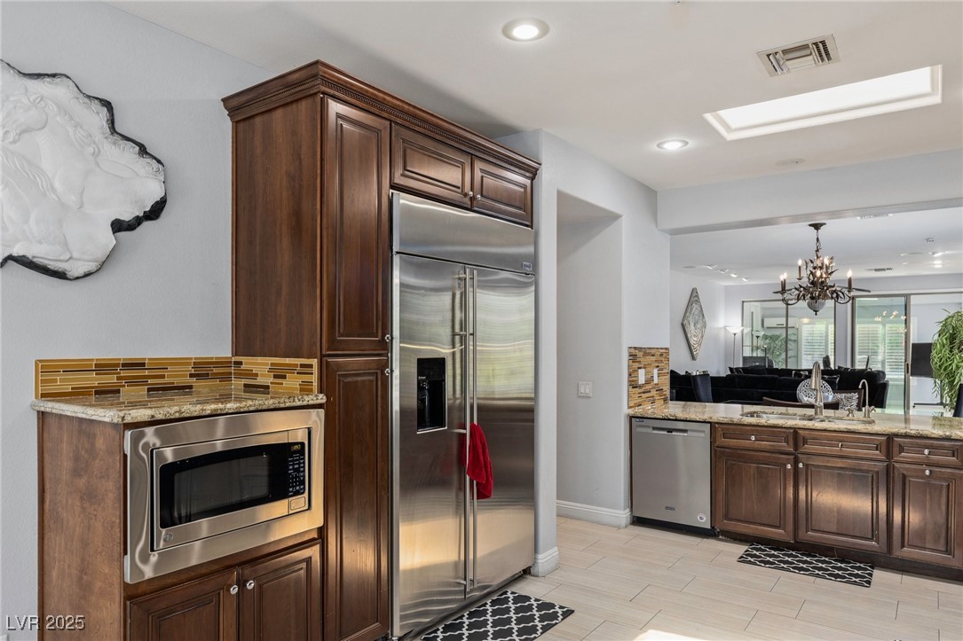 3 Chatmoss Road Henderson, NV 89052 - Photo 12 of 41 Kitchen with built in appliances, decorative backsplash, a sink, a chandelier, and light stone counters