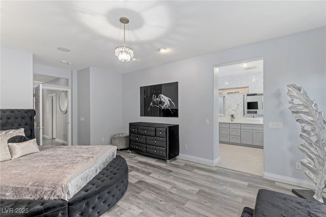 3 Chatmoss Road Henderson, NV 89052 - Photo 29 of 41 Bedroom with light wood-style floors, baseboards, an inviting chandelier, and ensuite bathroom