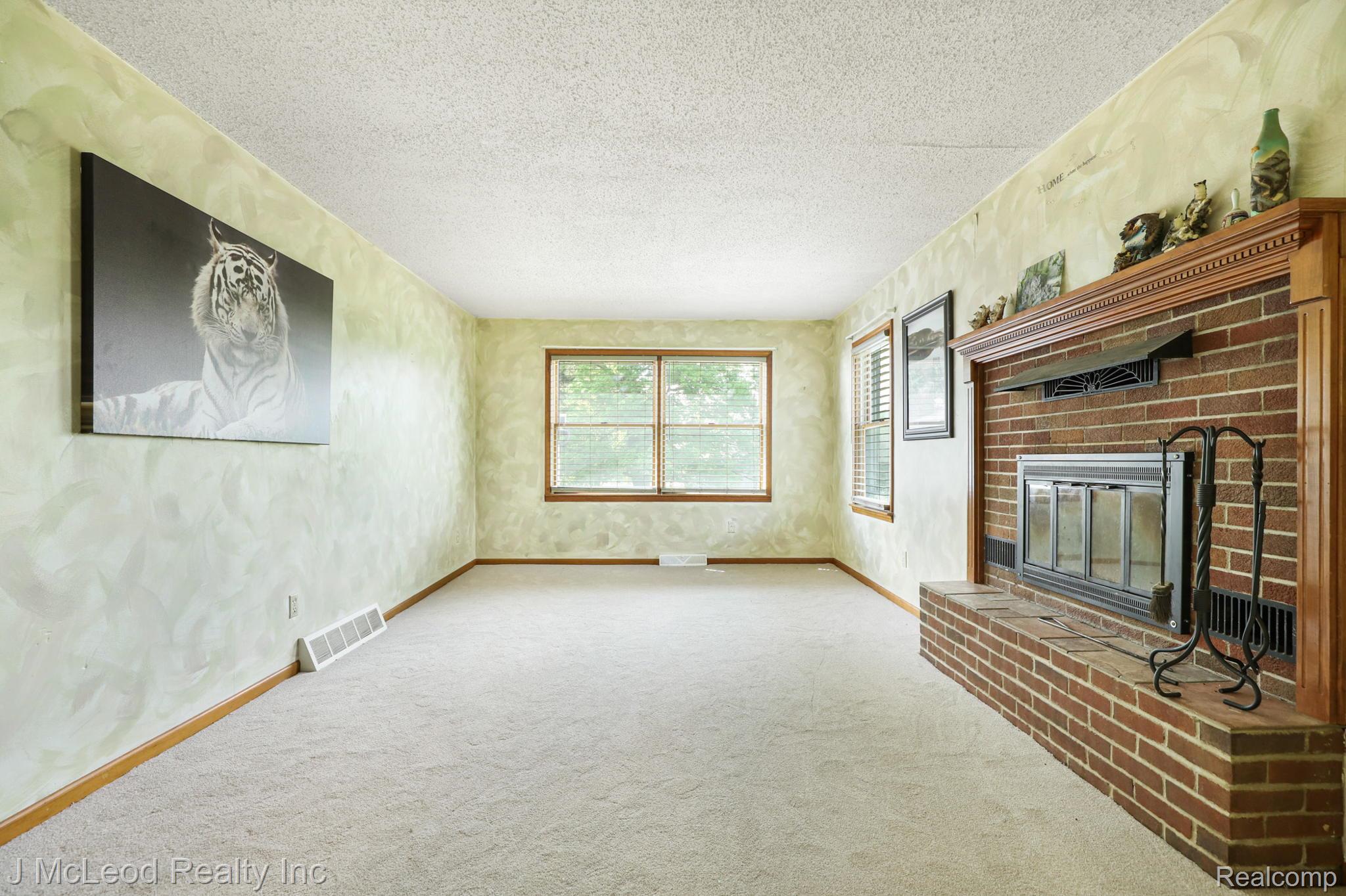 69 West Snover Road Mayville, MI 48744 - Photo 9 of 46 Brick fireplace with a wood mantle, neutral carpeting, and multiple windows