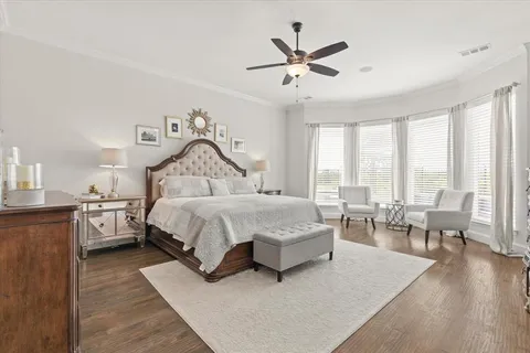a spacious bedroom with a bed a large window with table and chair