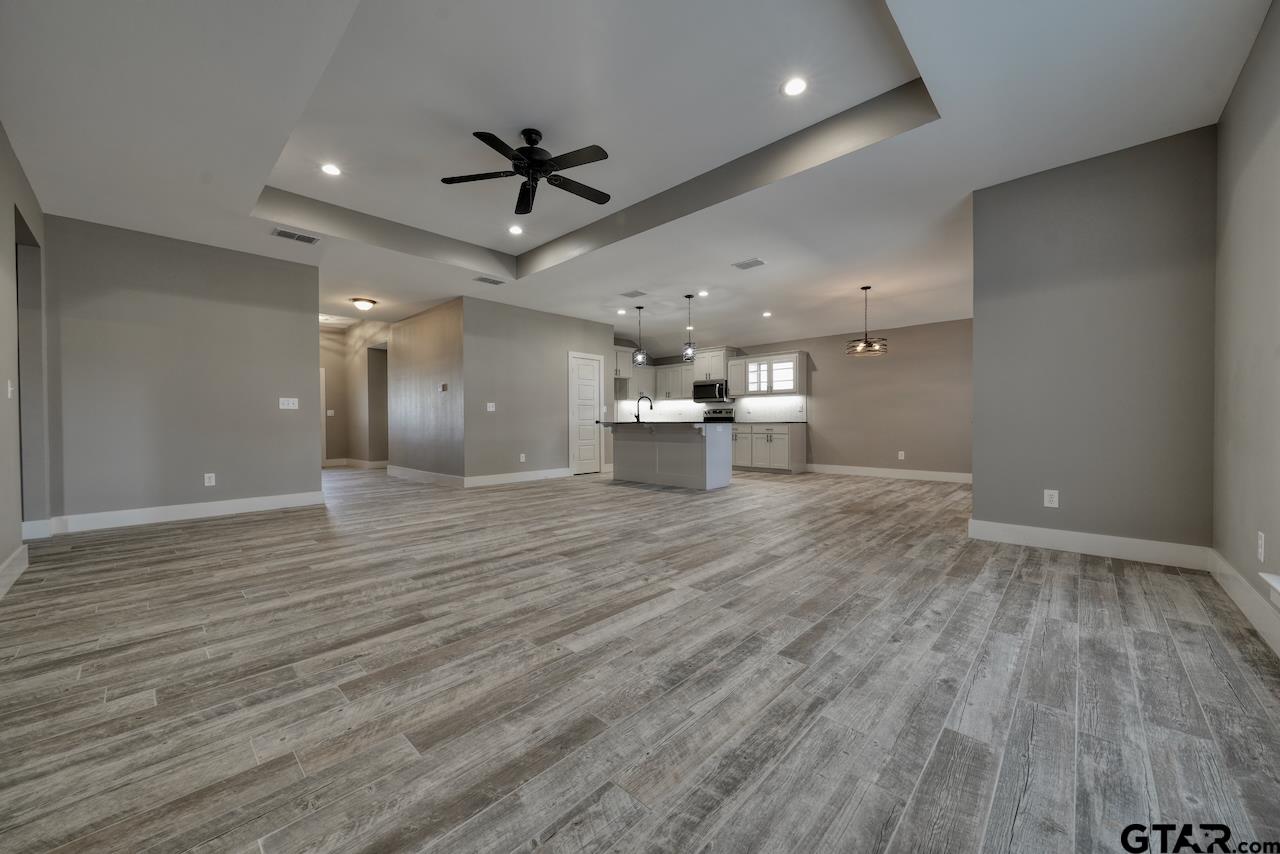 15342 Spring Oaks Drive Lindale, TX 75771 - Photo 12 of 45 a view of a big room with wooden floor a ceiling fan and windows
