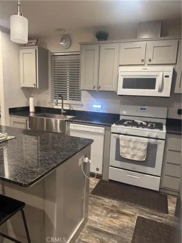 a kitchen with granite countertop a stove a sink and a microwave