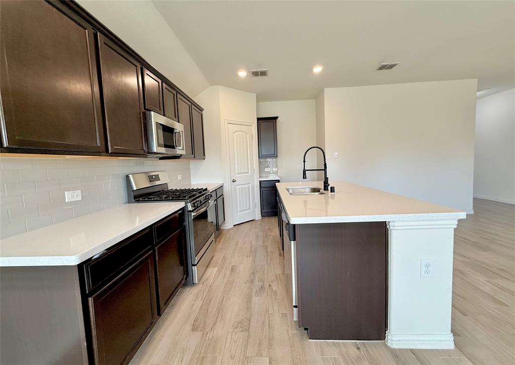 813 Evergreen Street Princeton, TX 75407 - Photo 20 of 29 a kitchen with stainless steel appliances a sink a stove top oven a counter space and cabinets