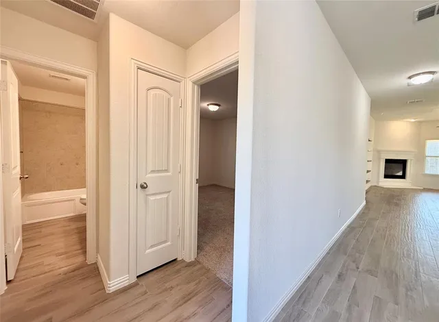 a view of a hallway with wooden floor and closet area