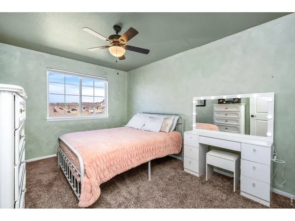 a bedroom with a bed and a ceiling fan with a dresser