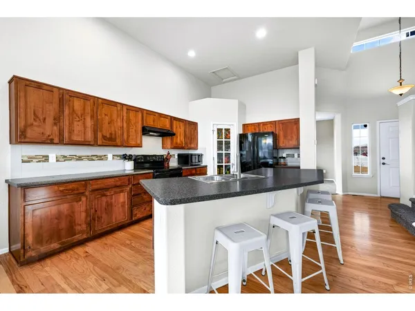 a kitchen with stainless steel appliances kitchen island granite countertop a stove a sink dishwasher and a microwave oven with wooden cabinets