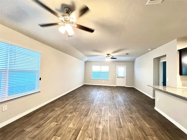 a view of an empty room with window and wooden floor