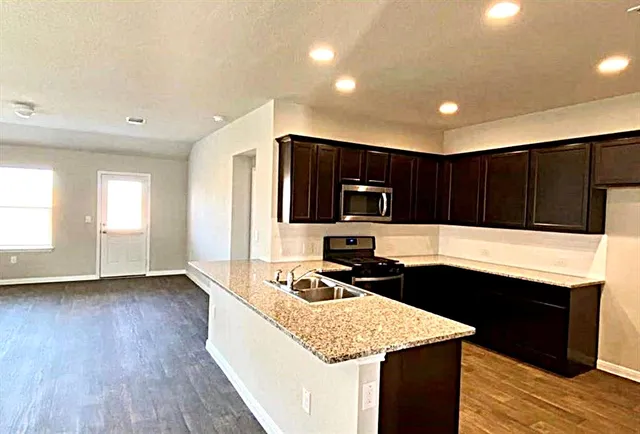 a kitchen with a sink and a stove top oven with wooden floor