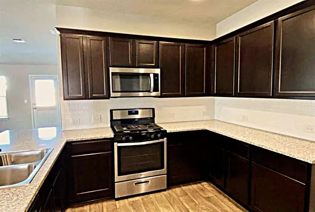 a kitchen with granite countertop a stove and a microwave