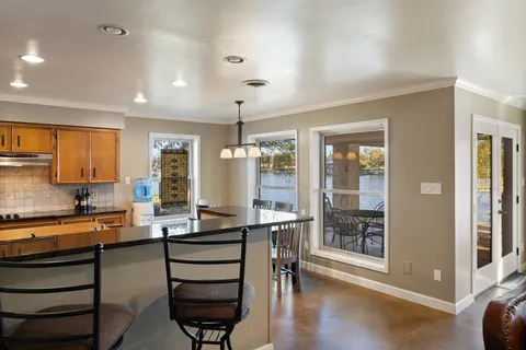 a room with stainless steel appliances kitchen island granite countertop a stove and a view of living room