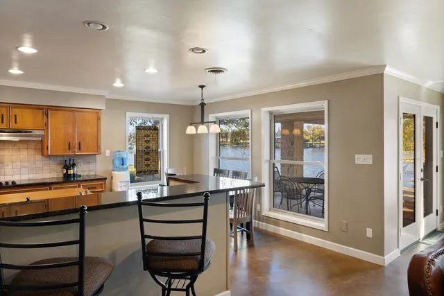 a room with stainless steel appliances kitchen island granite countertop a stove and a view of living room