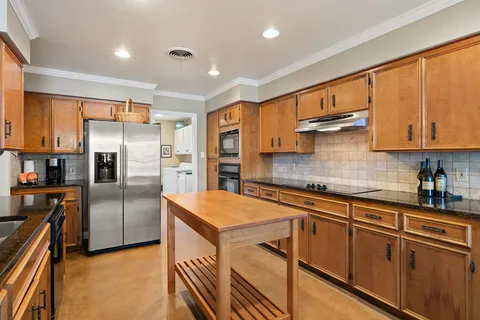 a kitchen with stainless steel appliances granite countertop a refrigerator a sink a stove a microwave and island