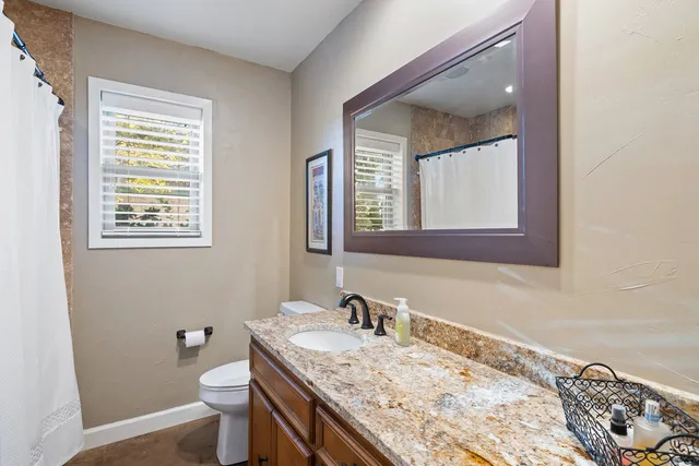 a bathroom with a granite countertop sink toilet and mirror