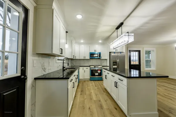 a large kitchen with cabinets a sink a window and stainless steel appliances