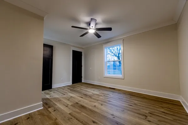 a view of empty room with wooden floor and fan