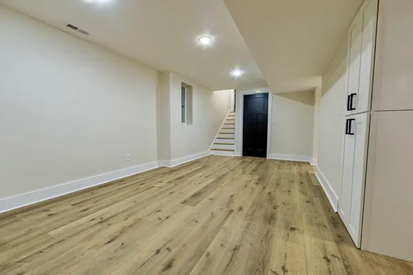 an empty room with wooden floor and bathroom