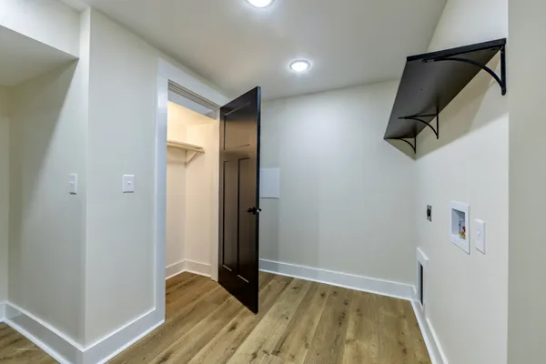 a view of hallway with walk in closet and wooden floor