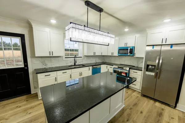 a kitchen with stainless steel appliances granite countertop a sink a stove top oven a counter space and cabinets