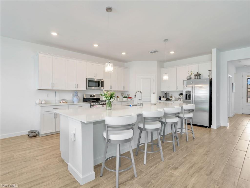 18278 Ridgeline Drive Estero, FL 33928 - Photo 7 of 45 a kitchen with stainless steel appliances kitchen island granite countertop a dining table chairs refrigerator sink and cabinets