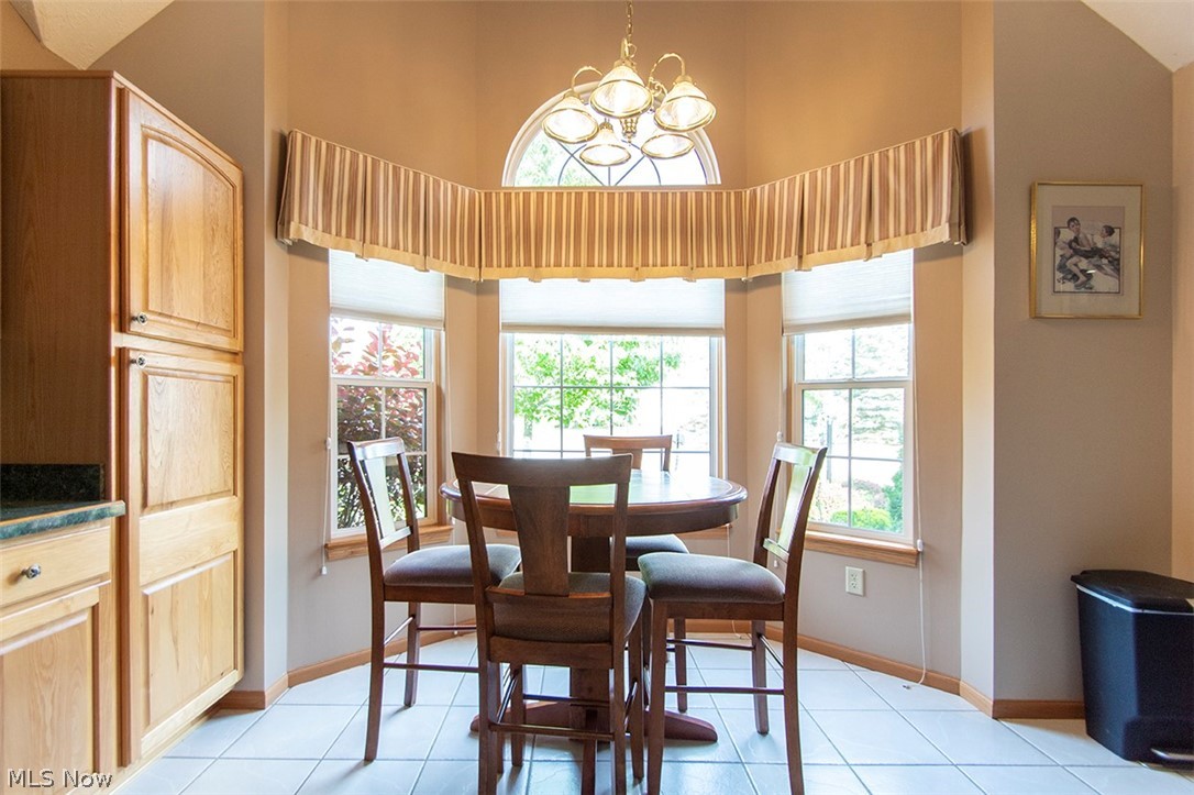 4902 Foote Road, Unit 21 Medina, OH 44256 - Photo 5 of 34 Dining area with high vaulted ceiling, light tile floors, and a chandelier