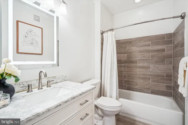 a bathroom with a granite countertop sink a toilet and shower
