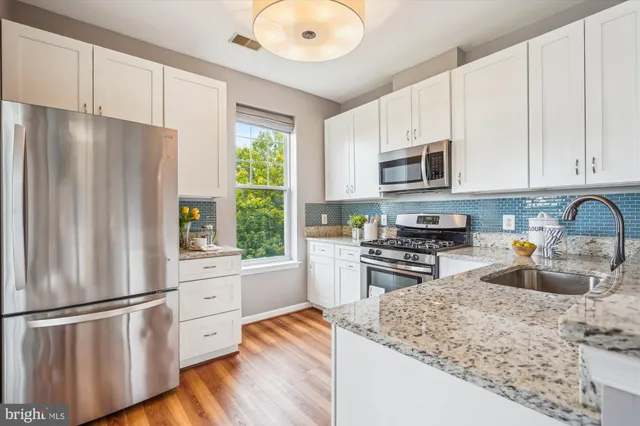 a kitchen with stainless steel appliances granite countertop a refrigerator sink and stove