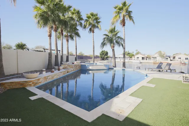 a view of a swimming pool with a lawn chairs and palm tree