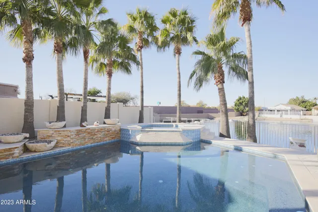 a view of a swimming pool with a lawn chairs and palm tree