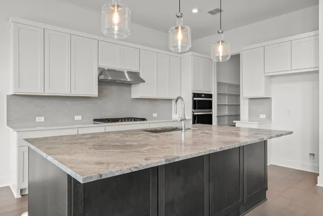 a kitchen with stainless steel appliances granite countertop a sink dishwasher and white cabinets with wooden floor