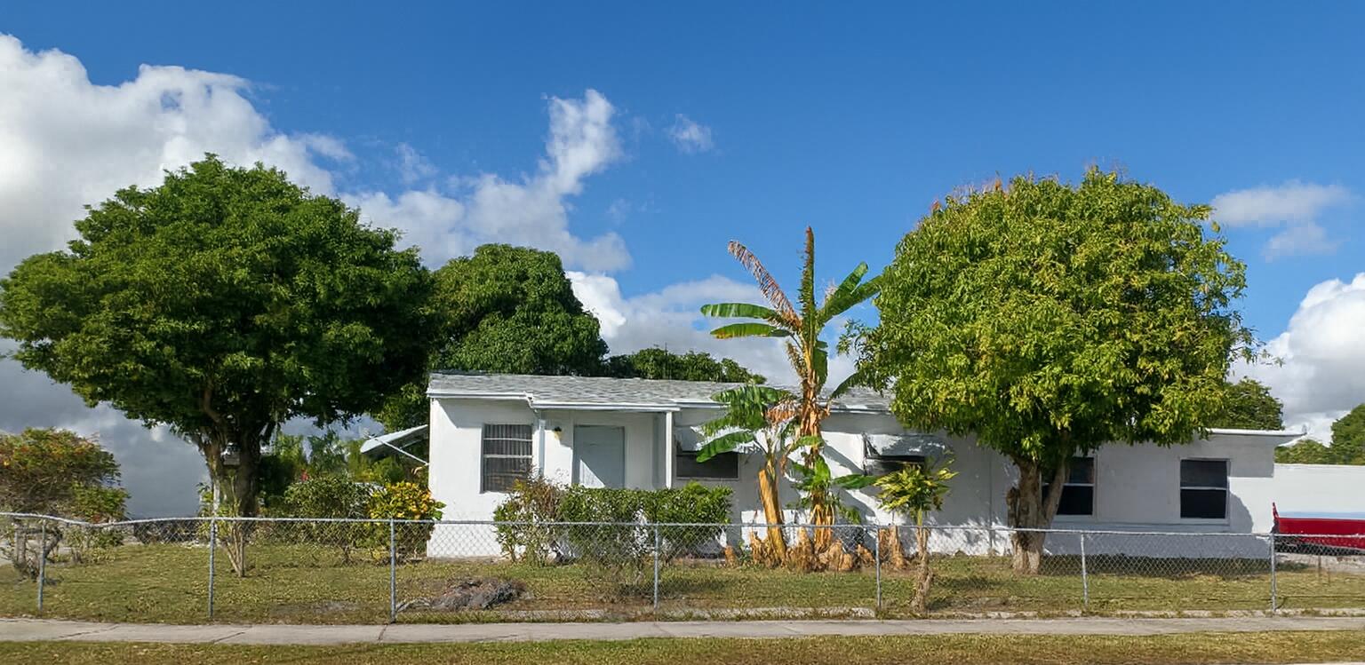 1060 West 26th Court Riviera Beach, FL 33404 - Photo 1 of 23 a front view of a house with a garden