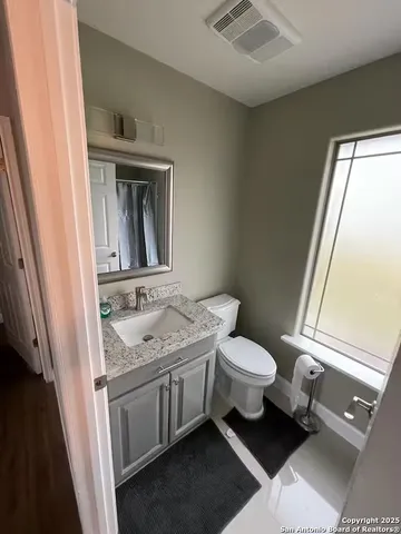 a bathroom with a granite countertop sink toilet and mirror