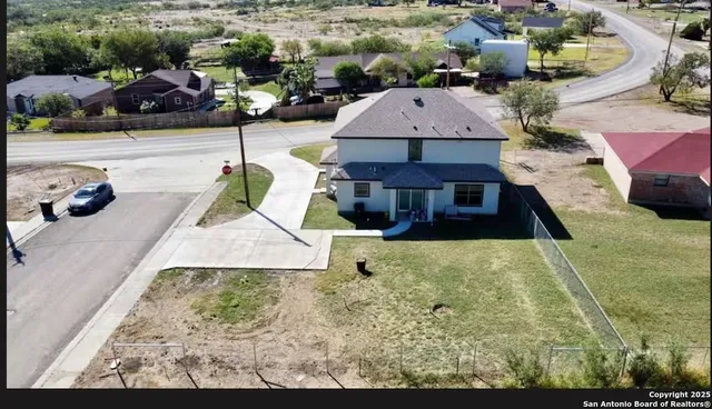 an aerial view of a house with swimming pool and large trees