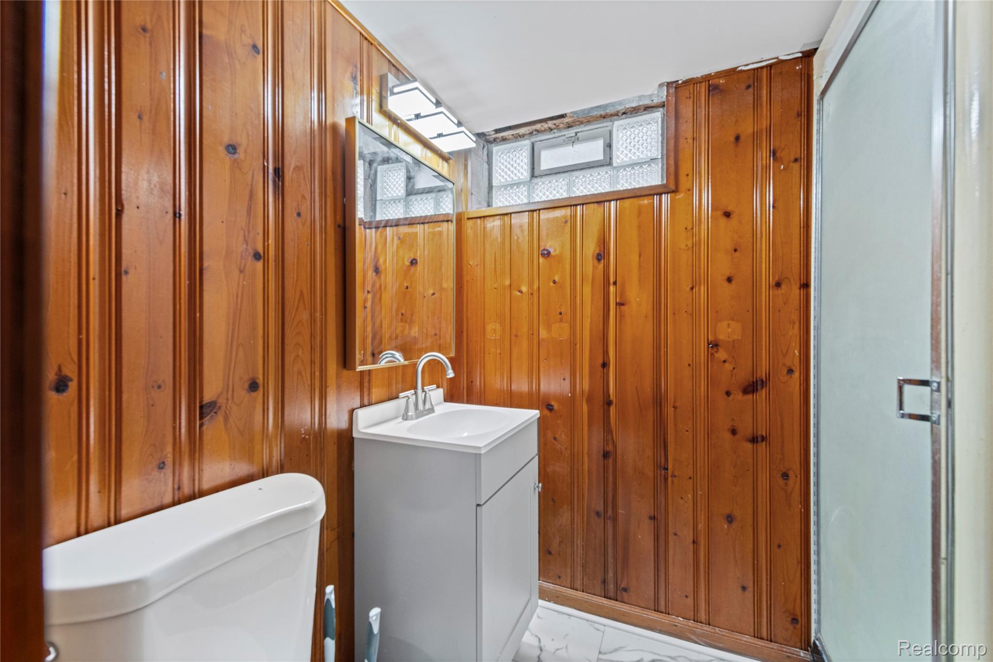 19720 Edinborough Road Detroit, MI 48219 - Photo 24 of 30 Half bathroom with vanity, wood walls, and light marble finish flooring