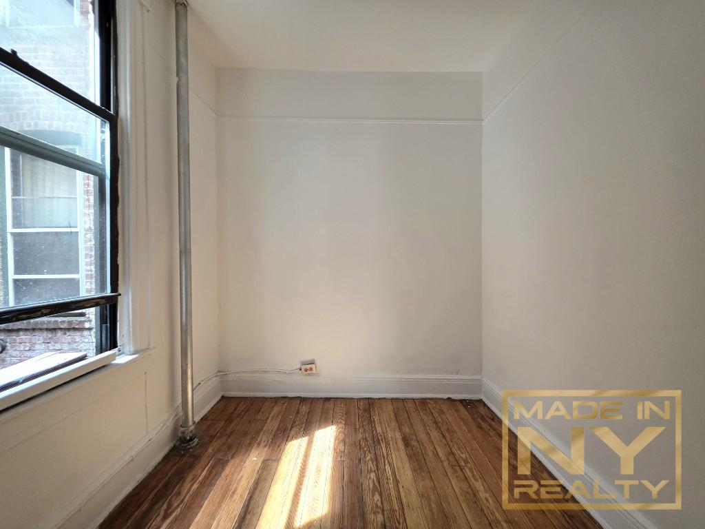 41-15 53rd Street, Unit E2 Queens, NY 11377 - Photo 6 of 7 a view of an empty room with wooden floor and a window