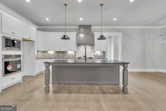 a large kitchen with stainless steel appliances a large counter top a stove a sink and a refrigerator