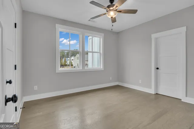 an empty room with windows and ceiling fan