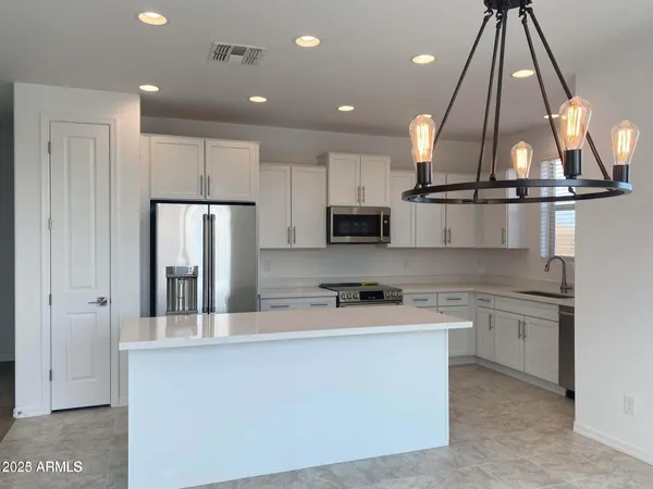 a kitchen with stainless steel appliances granite countertop a refrigerator a sink dishwasher a stove and white cabinets with wooden floor
