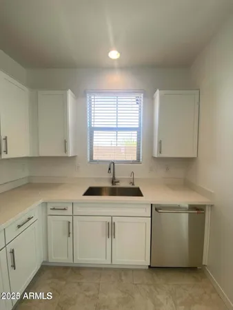 a kitchen with white cabinets appliances a sink and a window