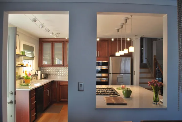 a kitchen with stainless steel appliances kitchen island granite countertop a dining table chairs and a refrigerator