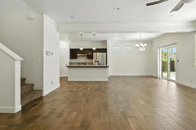 a view of a big room with wooden floor and a kitchen