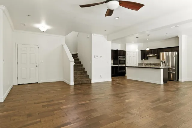 an empty room with wooden floor kitchen view and a window