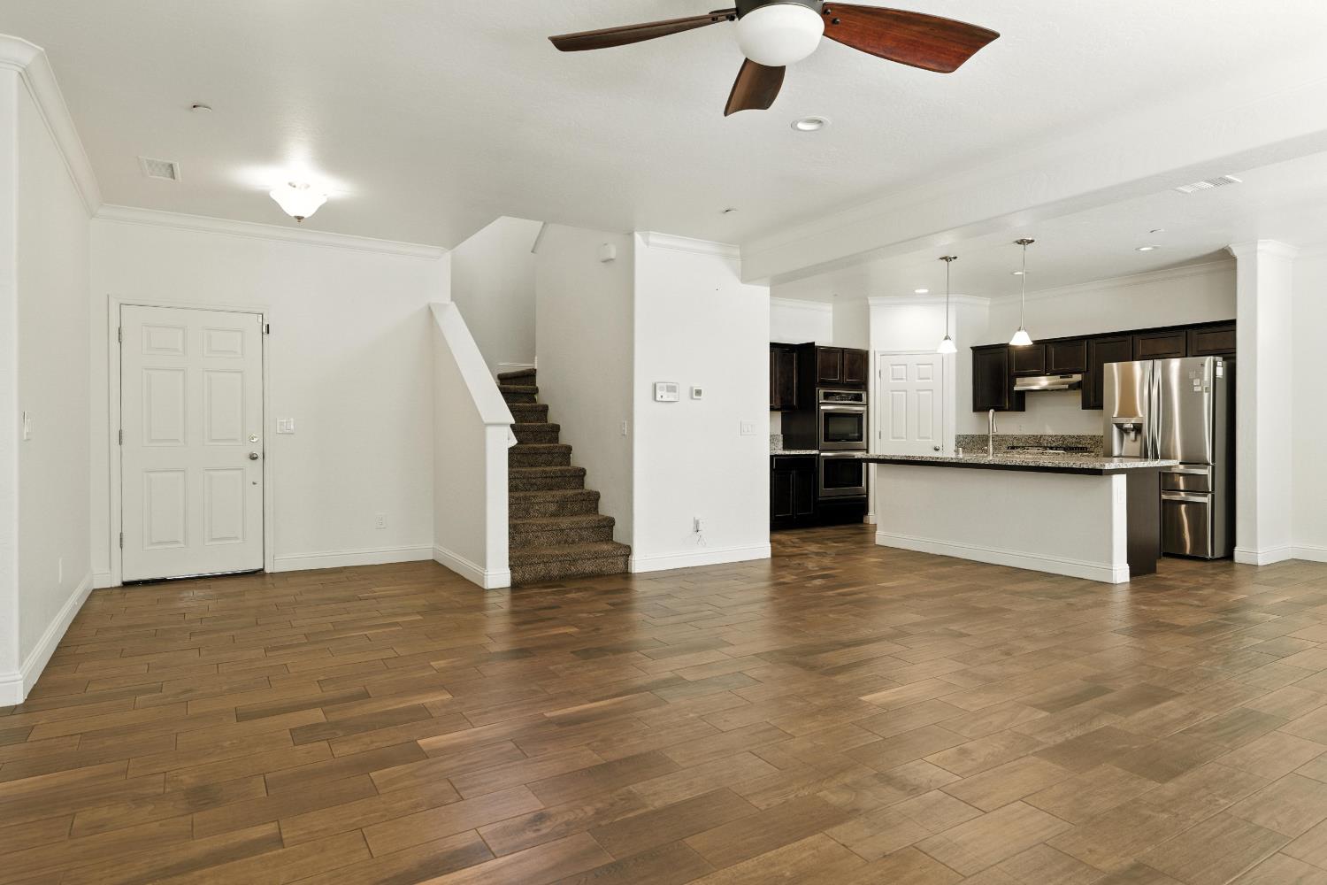 1732 Cleveland Street Selma, CA 93662 - Photo 5 of 24 an empty room with wooden floor kitchen view and a window