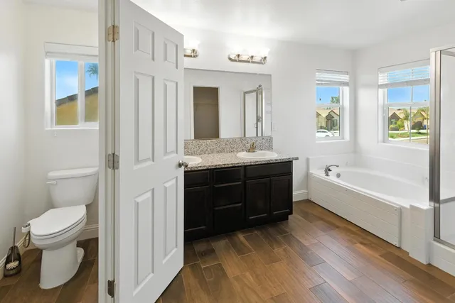 a spacious bathroom with a tub sink toilet and mirror