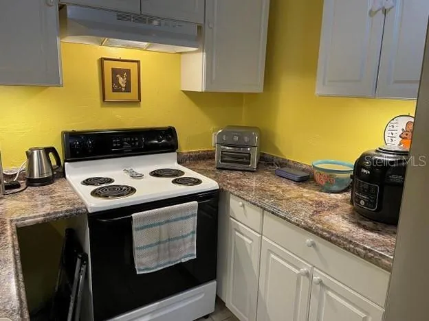 a kitchen with granite countertop a sink a stove and wooden cabinets