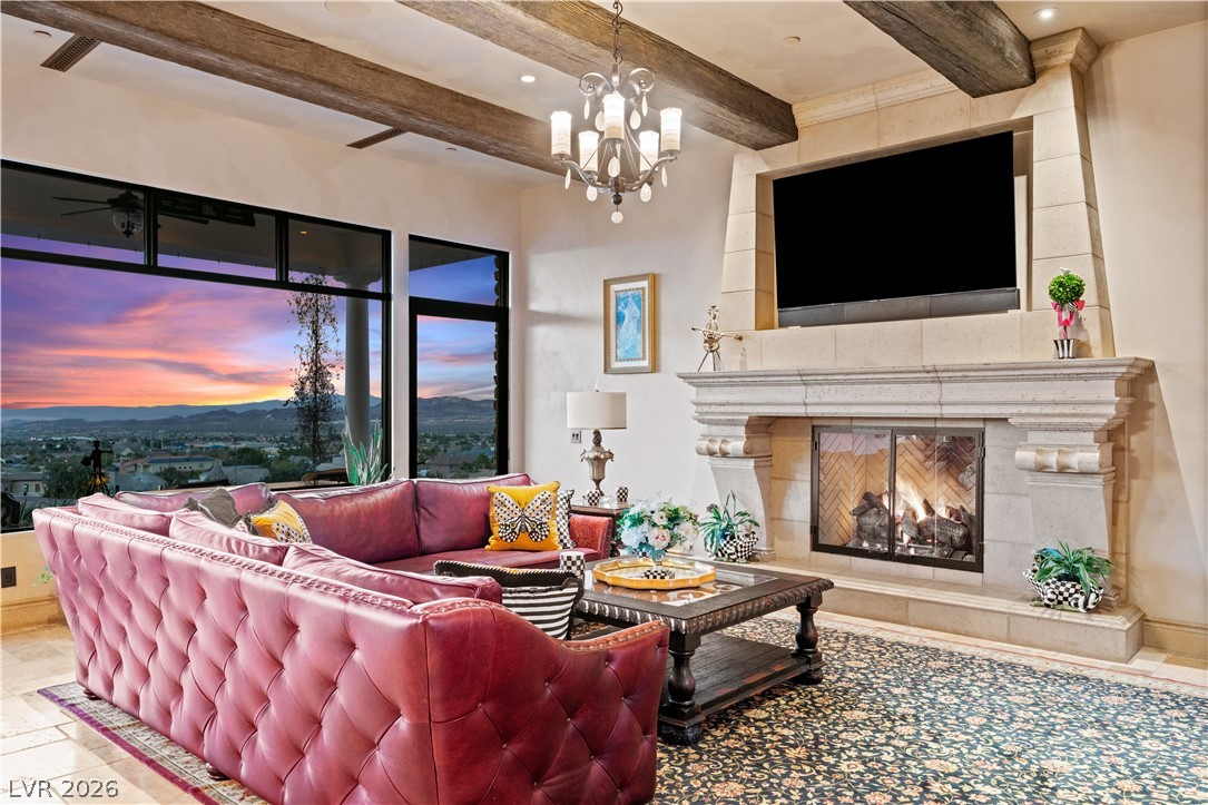 1123 Christian Road Henderson, NV 89002 - Photo 13 of 94 Dramatic sunset views perfectly frame this spacious living room, featuring a magnificent stone fireplace and exposed wood beams.