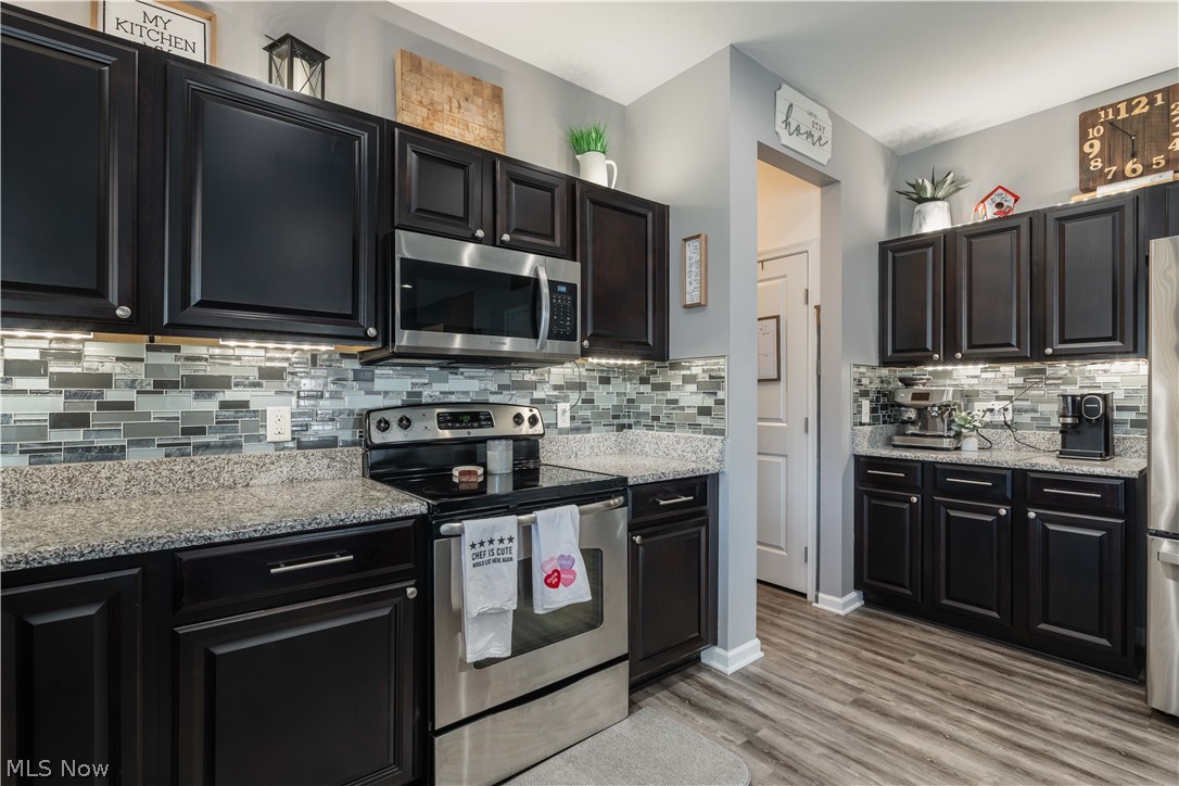 6687 List Street Northwest Canton, OH 44708 - Photo 9 of 21 Kitchen featuring stainless steel appliances, dark cabinetry, light stone counters, and backsplash