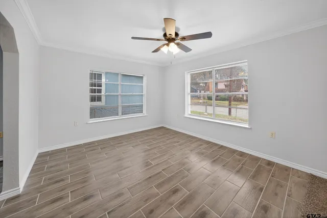 a view of an empty room with a window and wooden floor