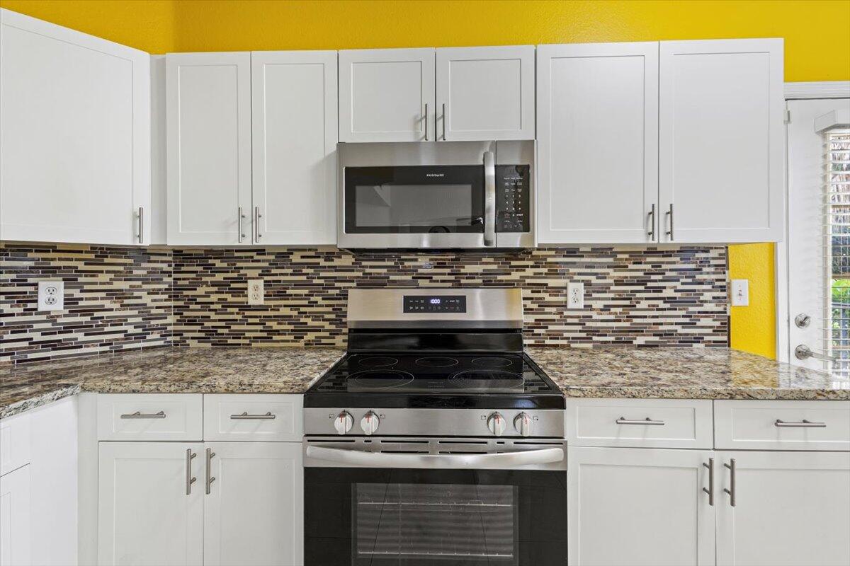 110 Southwest Peacock Boulevard, Unit 6101 Port St. Lucie, FL 34986 - Photo 22 of 70 a kitchen with granite countertop white cabinets and stainless steel appliances